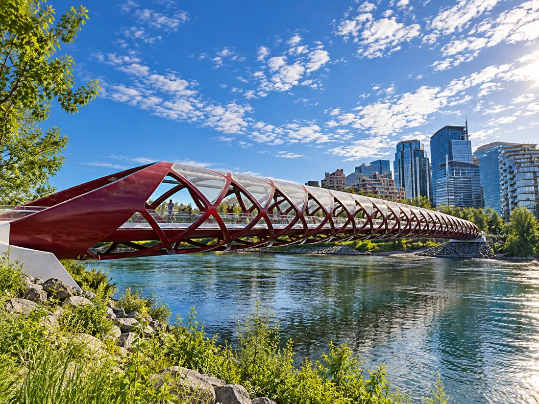 The red Peace Bridge crossing the Bow River on a sunny summer day, with Calgary’s downtown towers behind it.