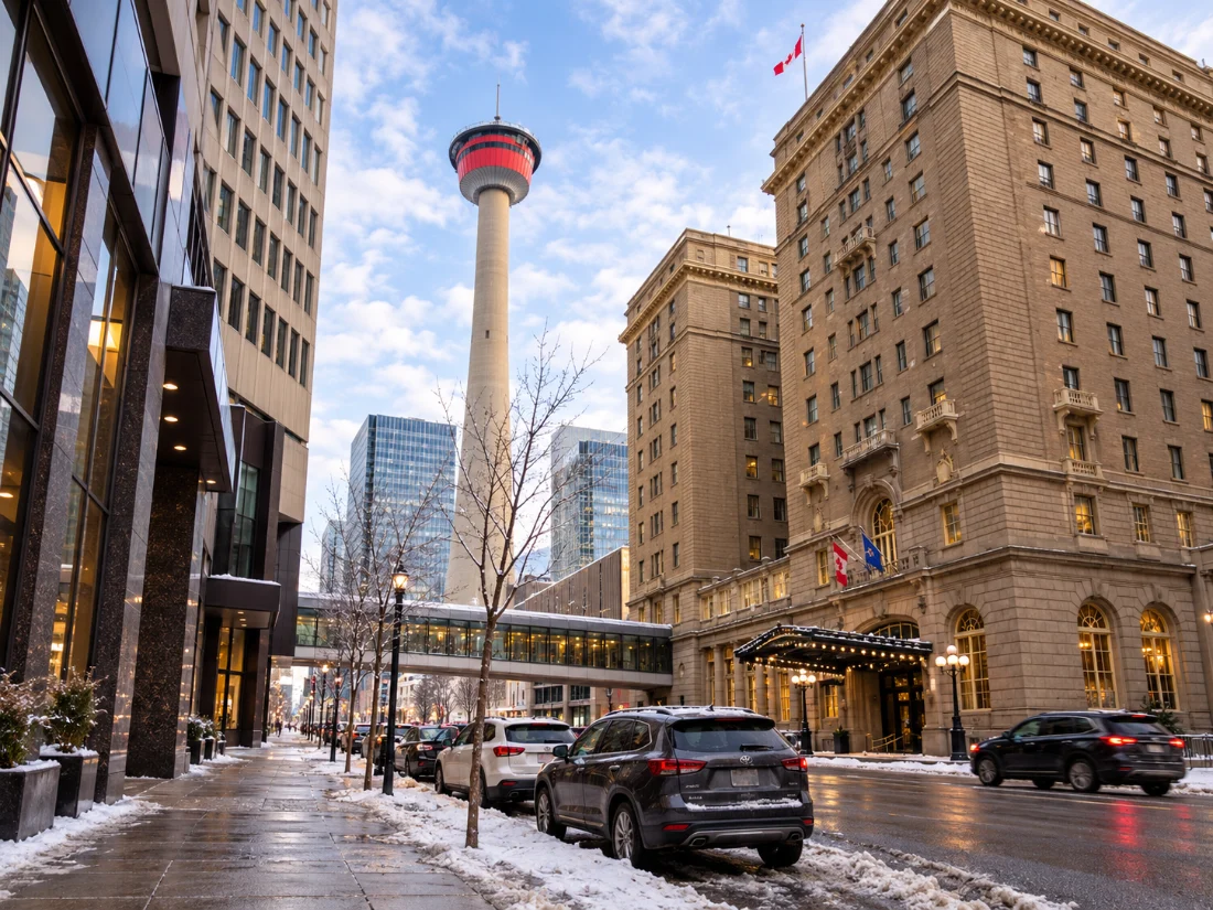 A snowy downtown Calgary street in winter, with the Calgary Tower rising between office buildings.